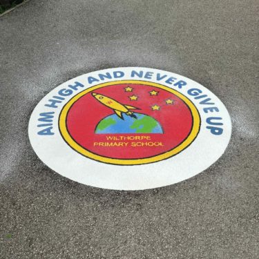 Red, white, and yellow thermoplastic school logo featuring a rocket on tarmac
