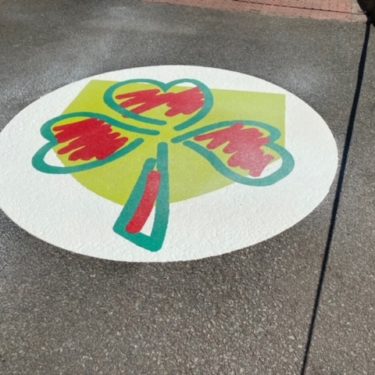Green and red clover design on tarmac playground